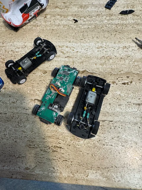 Tres chasis de coches RC abiertos; se ven los motores y una placa electrónica